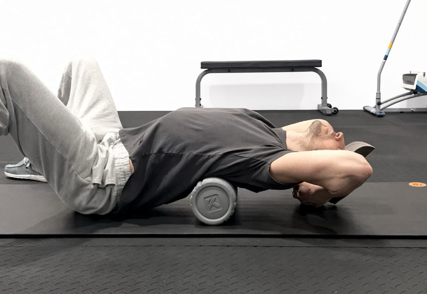 A client foam rolling his upper back on the studio floor